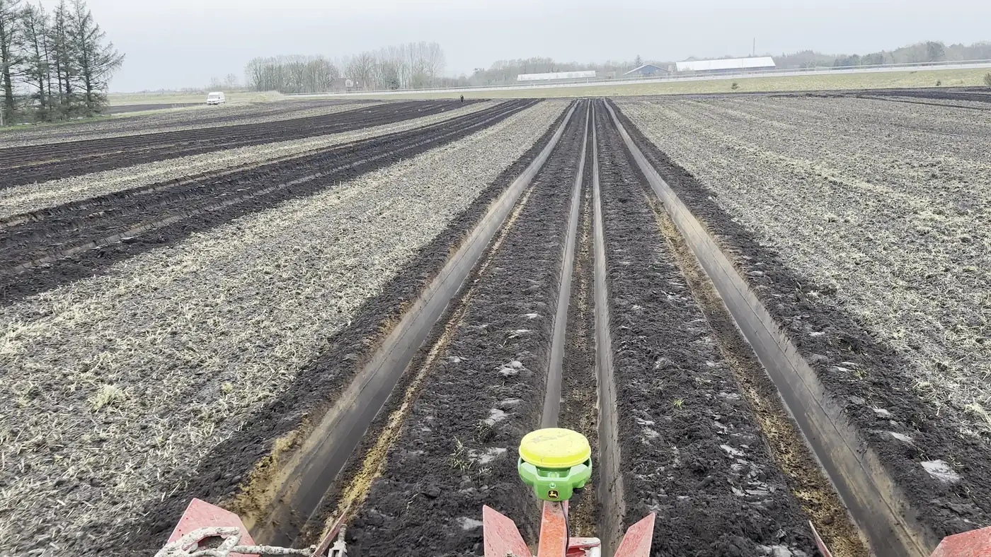 Looking back over an implement fitted with a GNSS receiver, cutting dead-straight beds to the horizon